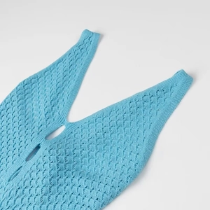Détail du haut sans manches en tricot bleu clair avec col en V et motif au crochet