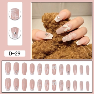 Kit de faux ongles à coller avec nœud papillon, perles et strass sur fond rose nu