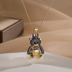 Gold-plated bear pendant necklace with purple and black zircon stones on satin background