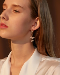 Detailed view of lily of the valley earrings with white flower petals and green leaves