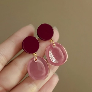 Detail of burgundy and translucent pink resin drop earrings with gold metal connector