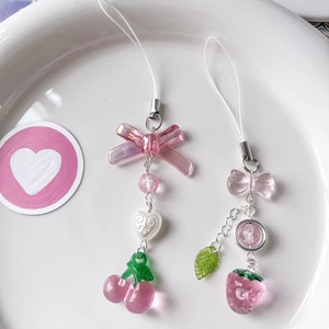 Pink cherry and strawberry phone charms with acrylic bows and beads on a white tray