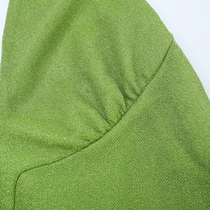 Détail de la robe vert herbe montrant le tissu métallique scintillant et les plis délicats