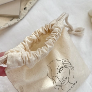 Close-up of beige cotton drawstring pouch with minimalist female line art and texture