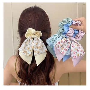 Detail showing various floral bow hair ties in yellow, blue and pink fabric on a model