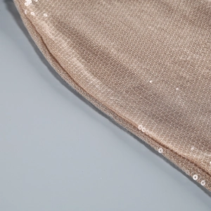 Détail macro de paillettes dorées champagne haute densité sur le tissu de robe de soirée
