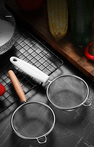 Detail of fine mesh stainless steel strainers with ergonomic wood and white handles