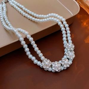 Double-layered pearl choker necklace with silver flower crystal pendants on a tray