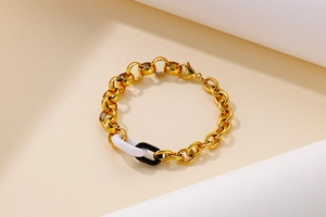 Détail de maillons dorés avec anneaux en résine blanc et noir sur un bracelet tendance