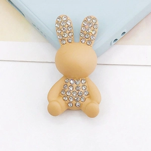 Vista macro di un accessorio per telefono a forma di coniglio beige con strass lucidi