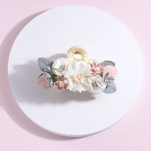 Detailed view of floral shark hair clip with white satin flowers, pearls and crystals