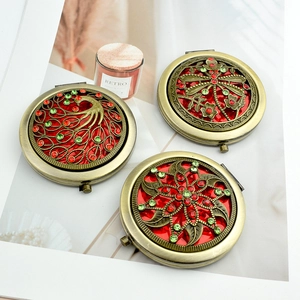 Vintage bronze compact mirrors with peacock and floral rhinestone designs on white background
