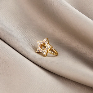Macro detail of golden star-shaped non-pierced clip nose ring with zircon stones on silk