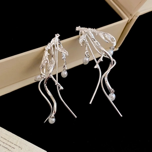 Detail shot of silver branch earrings with pearls resting on a beige jewelry box