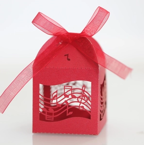 Gros plan sur boîte cadeau rouge avec notes de musique découpées et ruban organza