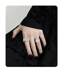 Detail of silver floral rings with pearls on hand against a black vintage background