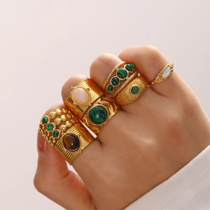 Close-up of vintage gold rings with green and brown gemstones worn by a model