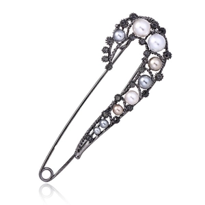 Macro detail of vintage safety pin brooch with multi-colored pearls and dark rhinestones