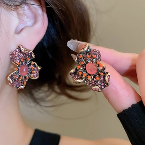 Gros plan sur des boucles d'oreilles fleur vintage en résine avec strass et oeil-de-chat