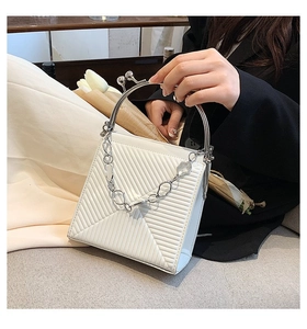 Detailed view of a white textured handbag with silver metal ring handle and chain detail