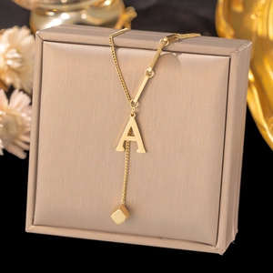 Detail of gold titanium steel necklace featuring letter A and square block pendant