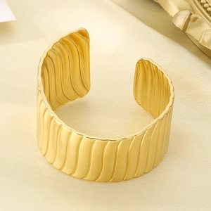 Detailed view of the vintage textured vertical wavy stripes on the wide gold cuff bracelet