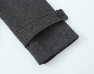 Détail du poignet d'un manteau en laine gris foncé avec sangle réglable et bouton noir