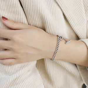 Silver Cuban link bracelet with OT toggle clasp worn on wrist against corduroy background