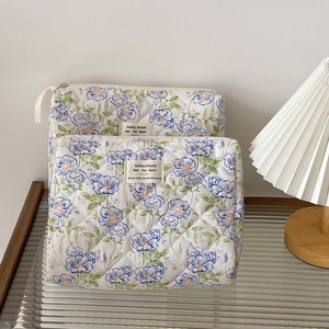 Quilted floral makeup bag set with blue flower patterns on a wooden table setup