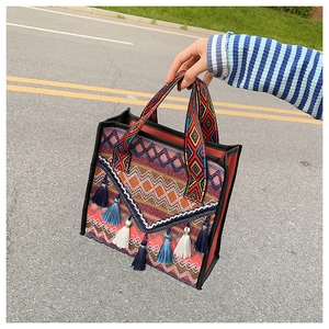 Detail view of ethnic bohemian bucket bag featuring colorful embroidery and tassels