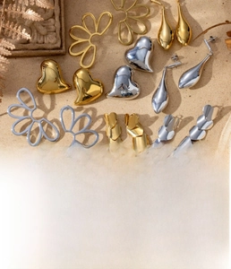 Detail showing titanium steel earrings with heart and floral designs in gold finish