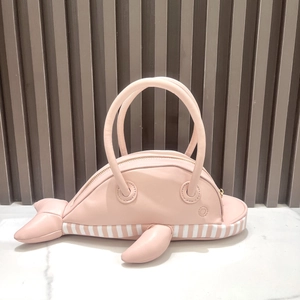 Detailed view of pink whale shaped handbag with white striped base and top handles