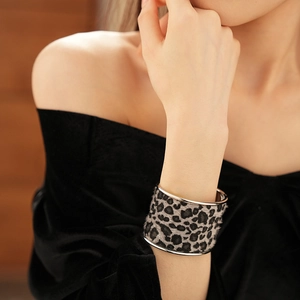 Close-up of leopard print wide cuff bracelet with silver trim on a model's wrist