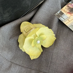 Detailed view of a yellow orchid hair claw clip with chiffon petals and a pearl center
