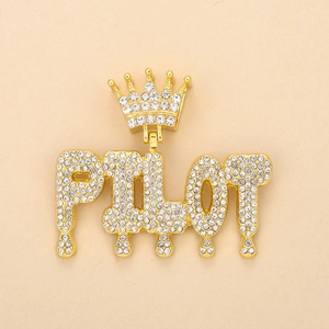 Macro view of gold-plated PILOT letter pendant with crown and dripping rhinestones