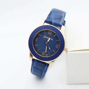 Macro detail of women's quartz watch showing blue leather strap and rose gold case