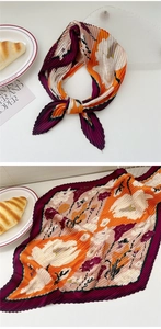 Close-up of pleated floral silk scarf with vibrant orange and magenta accordion folds
