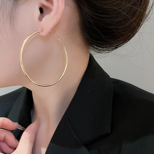 Close-up of model wearing large minimalist golden hoop earrings with a polished finish