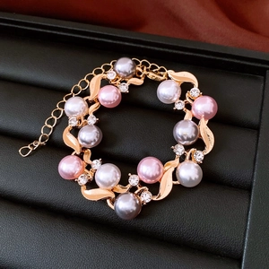 Detail shot of pink and gray pearls with sparkling crystals on a gold chain bracelet