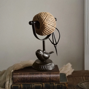 European vintage cast iron bird twine holder with antique books on wooden table