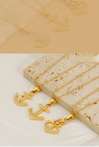 Detail of 18K gold plated anchor pendants with micro-paved zircons on stone surface