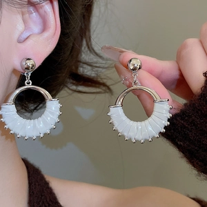 Detail of silver hoop earrings featuring white leather wrap and delicate bead trim
