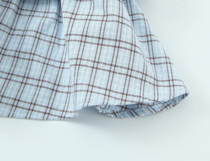 Detailed macro view of light blue plaid fabric with premium stitching and cotton texture