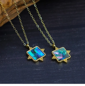 Macro detail of square abalone shell pendant on 18K gold plated necklace chain