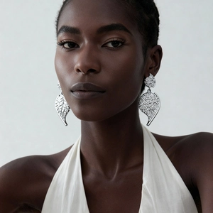 Close-up of a model wearing large silver-tone leaf earrings with detailed textured metal finish