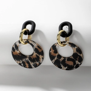 Détail des boucles d'oreilles léopard en résine avec anneaux dorés et clous noirs mats