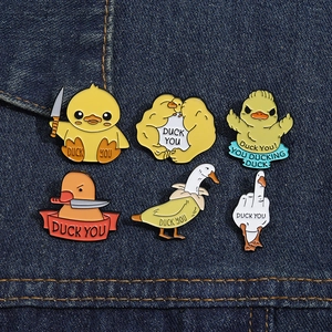 Detailed view of funny enamel duck pins with meme designs on blue denim fabric background