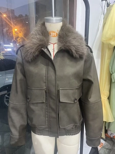Detail of dark olive faux leather jacket featuring large cargo pockets and plush faux fur collar