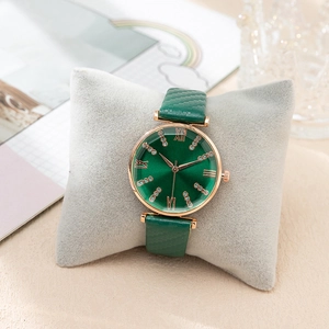 Elegant emerald green quartz watch with rose gold case and diamond accents on velvet pillow