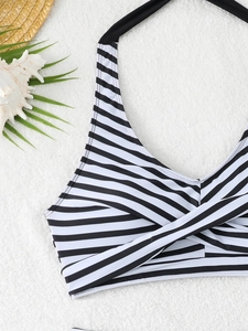 Dettaglio del top bikini a righe bianche e nere con nodo a incrocio sulla sabbia marina